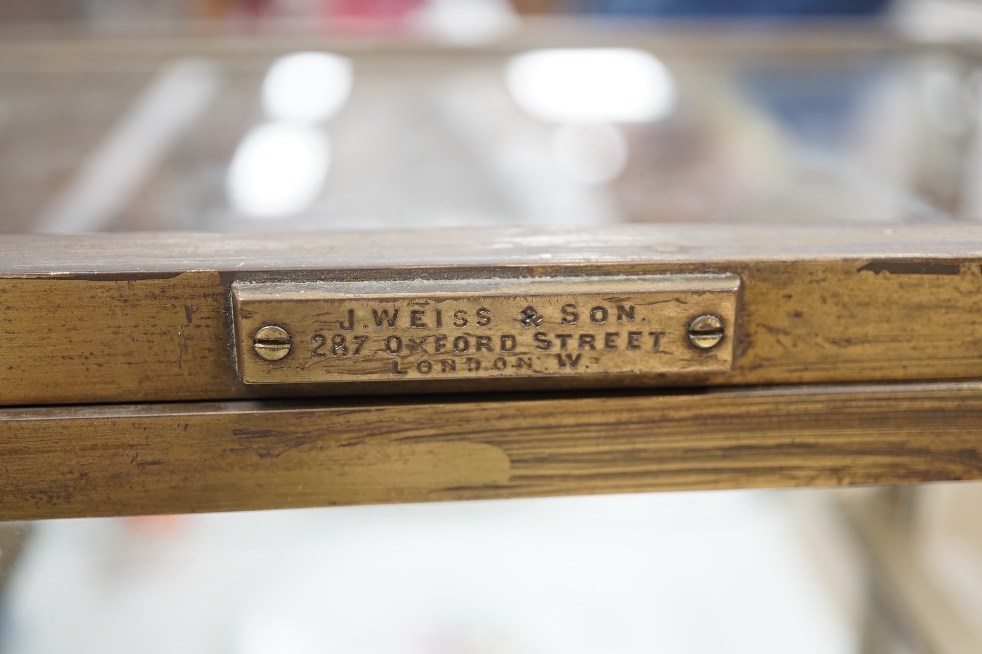 A small late 19th century brass display case, with glass shelf, bears plaque 'J Weiss & Son, 287 Oxford Street, London